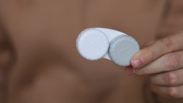 La chica sostiene un contenedor de lentes de contacto en su mano - Metraje, vídeo
