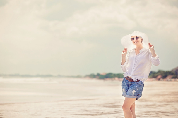Schöne junge Frau spaziert bei sonnigem Sommerurlaub am Strand entlang - Foto, Bild