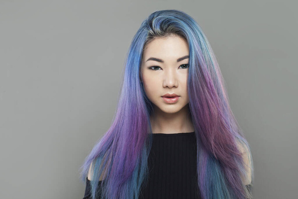 Houkutteleva nuori aasialainen nainen terve pitkä värillinen sininen ja violetti hiukset harmaalla pohjalla, studio muotokuva - Valokuva, kuva