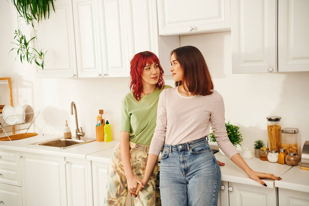 Intimate kitchen scene with a loving young lesbian couple sharing a moment of connection, bliss - Photo, Image