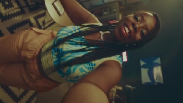 Vertical de mano pov disparo de la joven mujer afroamericana vistiendo colorido traje de estilo y2k bailando en sala de luz de neón - Metraje, vídeo