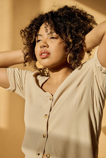 Eine schöne junge Afroamerikanerin mit lockigem Haar in einem Sommerkleid posiert selbstbewusst für ein Fotoshooting in einem Studio. - Foto, Bild