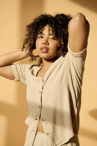 Une belle jeune afro-américaine aux cheveux bouclés pose élégamment pour une photo en studio. - Photo, image