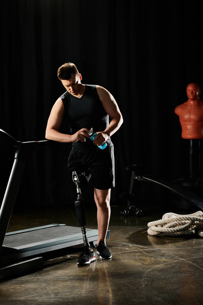 Чоловік, який займає протезну ногу, стоїть на біговій доріжці у смертельно освітленій кімнаті, зосередженій на тренуванні. - Фото, зображення