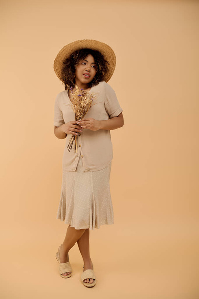 A beautiful young African American woman with curly hair wearing a straw hat and a summer dress, posing in a studio setting. - Photo, Image