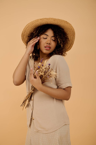 Piękna Afroamerykanka z kręconymi włosami, zakładająca słomkowy kapelusz i trzymająca żywy bukiet kwiatów. - Zdjęcie, obraz