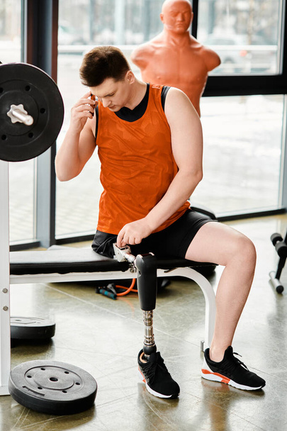 Człowiek z protezą nogi siedzi na ławce gimnastycznej, głęboko w myślach, otoczony energią siłowni.. - Zdjęcie, obraz