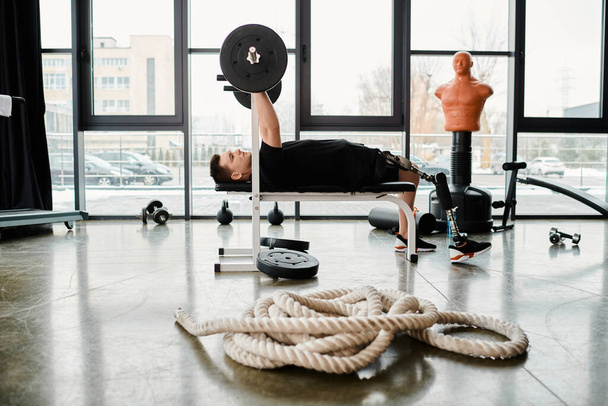 A disabled man with a prosthetic leg lies on a bench, facing a rope in front of him, in a determined workout session. - Photo, Image