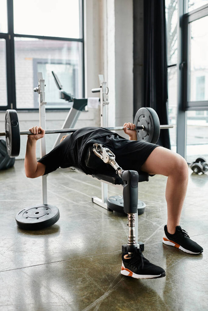 Mężczyzna z protezą nogi, podnoszący sztangę podczas wyciskania na ławce w siłowni. - Zdjęcie, obraz