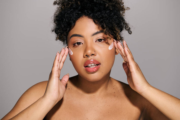 Una joven afroamericana con el pelo rizado sosteniendo sus manos hacia su cara en una pose reflexiva. - Foto, imagen
