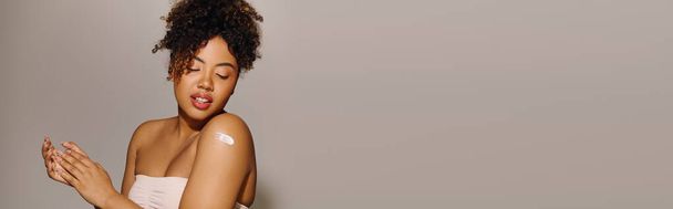 Μια εκπληκτική Αφρο-Αμερικανίδα με λευκό φόρεμα που ποζάρει απαλά, αποπνέοντας κομψότητα και χάρη. - Φωτογραφία, εικόνα
