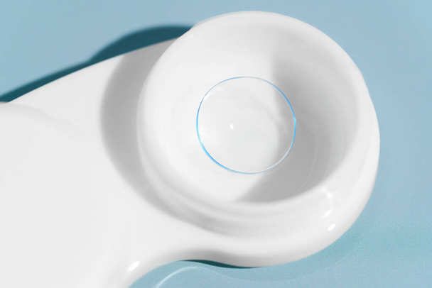 Mavi arka plandaki beyaz bir konteynırda şeffaf bir kontakt lensin yakın çekimi. Görüş iyileştirme konsepti, göz hekimi ve tedavi, göz bakımı - Fotoğraf, Görsel