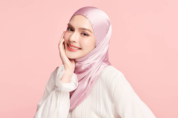 Schöne junge asiatische Muslimin trägt einen rosafarbenen Hijab auf rosa Hintergrund, Portrait of Arab Beauty. - Foto, Bild