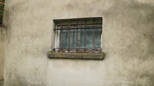 Une petite fenêtre couverte d'une calandre rouillée sur le mur d'une maison en pierre. Des images FullHD de haute qualité - Séquence, vidéo