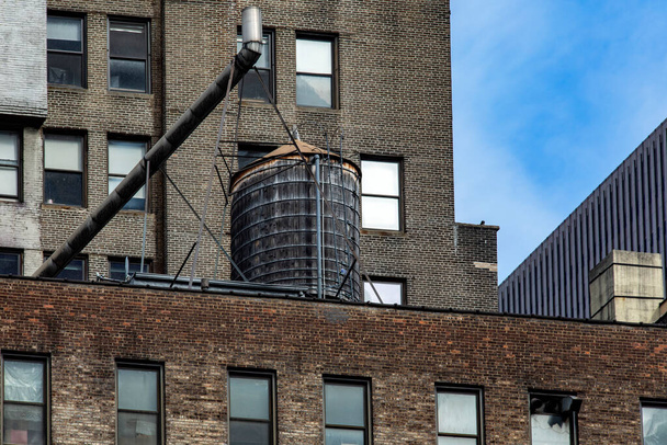 New York 'taki binaların çatısına tipik bir su tankı monte edildi (ABD). - Fotoğraf, Görsel
