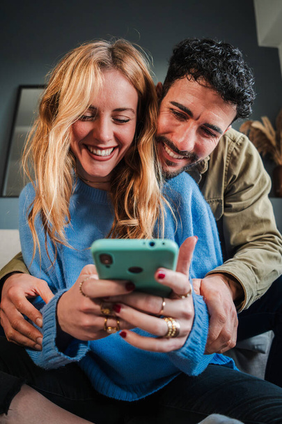 Vertical.Young valkoihoinen pari käyttää matkapuhelinta tehdä ostoksia verkossa. Mies ja nainen katsomassa sosiaalista mediaa älypuhelimella. Aikuiset ystävät hauskaa selailu internetissä matkapuhelimen kanssa - Valokuva, kuva