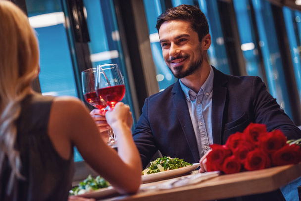 Hombre elegante guapo está mirando a su novia y sonriendo mientras tienen una cita en el restaurante
 - Foto, Imagen