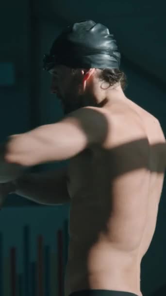 Středně svislé záběry svalnatého sportovce zahřívajícího se u bazénu, rotujícího trupu, ohýbajícího se, držícího se potápěčského bloku a protahujícího se svalů v jádře těla - Záběry, video