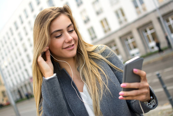Mujer joven con auriculares escuchando música en la calle. - Foto, imagen