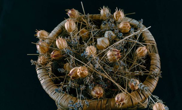 Cesta hecha de material vegetal llena de flores secas de diferentes tamaños - Foto, imagen