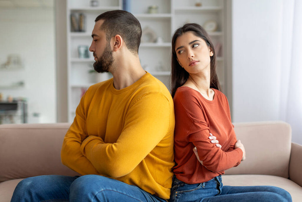 A man and woman show signs of a disagreement, sitting on a couch with arms folded, facing away - Photo, Image