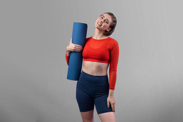 Full body length gaiety shot athletic and sporty young woman with fitness matt in exercise posture on isolated background. Healthy active and body care lifestyle. - Photo, Image