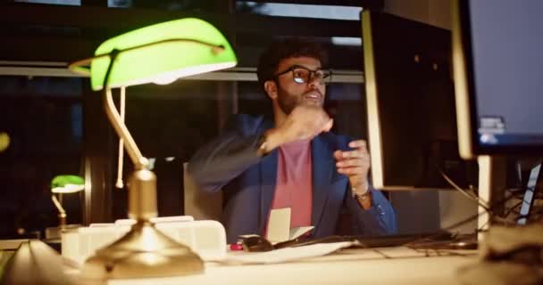 Soustředěný mužský podnikatel pilně pracuje po pracovní době v matně osvětlené kanceláři, ilustrující pozdní obchodní závazek a zdůrazňující oddanost profesním povinnostem. - Záběry, video