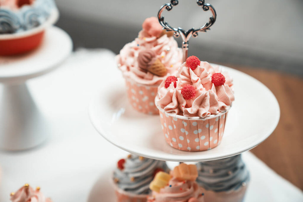Pièce de présentation de cupcake sur gâteau blanc debout avec pot à thé mis en concept de couleurs pastel cuisine spéciale. Contenu créatif des médias sociaux avec plat préféré de boulangerie de bonbons. Tastemaker. - Photo, image