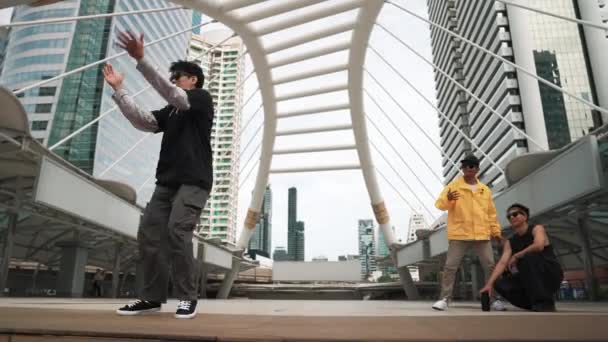 Egy csapat profi multikulturális táncos felvidul, miközben ázsiai hipszter lép fel a városi városban, alacsony szögletű kamerás emberekkel körülvéve. Break tánc koncepció. Kültéri sport 2024. Élénk.. - Felvétel, videó