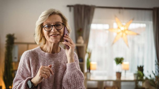 Jedna zralá blondýna žena stát doma používat mobilní telefon talk - Fotografie, Obrázek