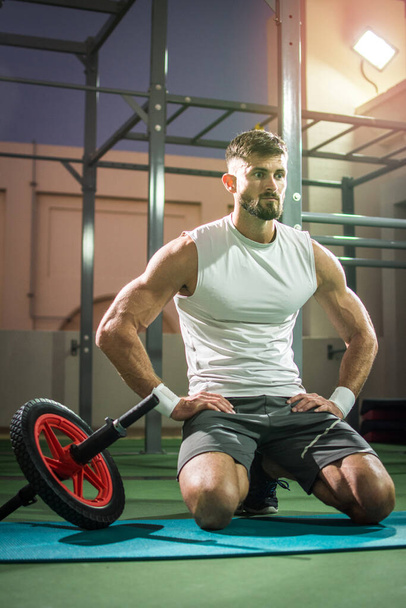 Jóképű férfi tart egy kis szünetet után fitness kerék edzés szabadtéri edzőteremben. - Fotó, kép