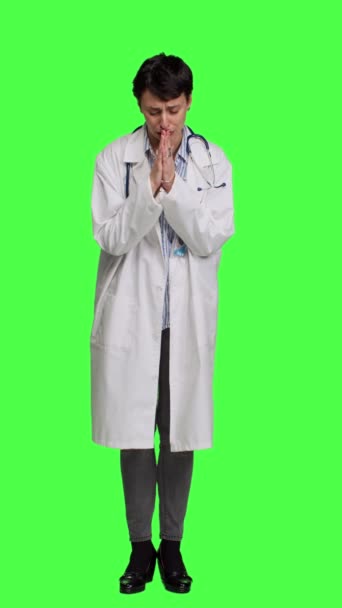 Előnézet Remélhetőleg az orvos fogja a kezét egy imajelben a zöld háttér ellen, és a stúdióban kér békét és megbocsátást. A fehér köpenyes női orvos meditál. A kamera. - Felvétel, videó