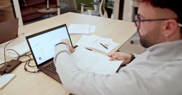 Homme d'affaires concentré analysant des graphiques sur ordinateur portable dans un bureau moderne, planification de la rentabilité et de la croissance de l'entreprise, concept de collaboration d'équipe. - Séquence, vidéo