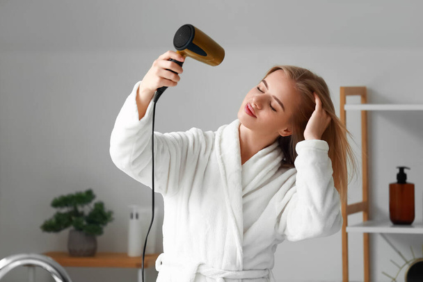 Csinos fiatal nő szárítás haj a fürdőszobában - Fotó, kép