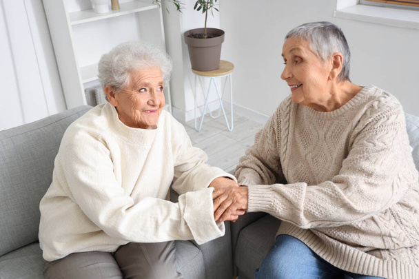 Idősebb női barátok fogják egymás kezét otthon. - Fotó, kép