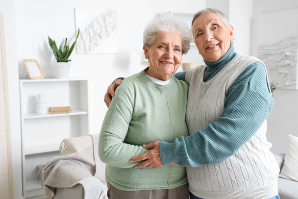 Старші друзі-жінки обіймаються вдома - Фото, зображення