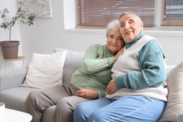 Старші друзі-жінки обіймаються на дивані вдома - Фото, зображення
