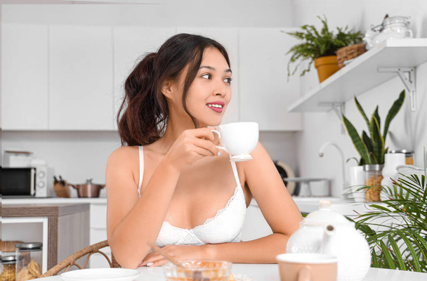 Attractive young Asian woman wearing white underwear with coffee cup in kitchen - Foto, imagen