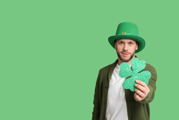 Jeune homme en chapeau de lutin avec trèfle sur fond vert. Célébration de la Saint Patrick - Photo, image