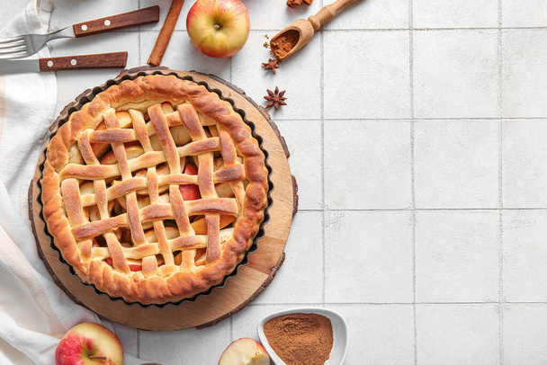 Смачний домашній яблучний пиріг з фруктами, корицею та столовими приборами на фоні білої плитки - Фото, зображення