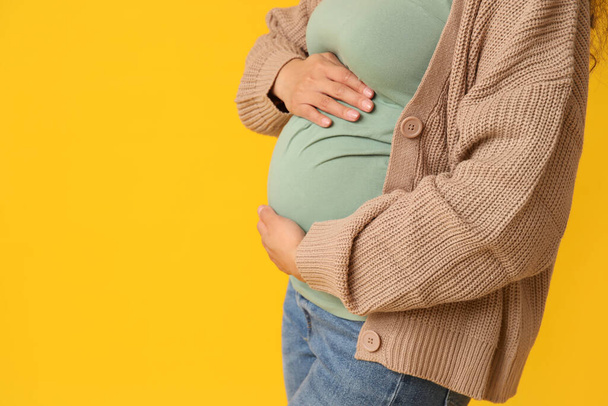 Joven embarazada afroamericana sobre fondo amarillo - Foto, imagen