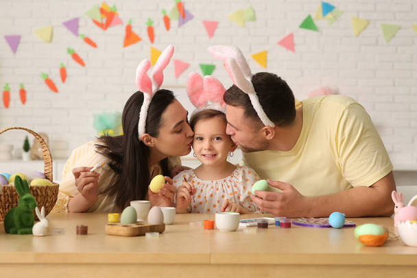 Tavşan kulaklı mutlu bir aile evde paskalya yumurtası boyuyor. - Fotoğraf, Görsel