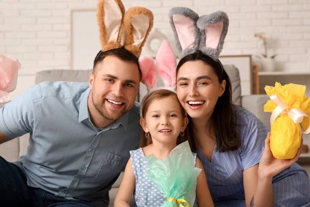 Szczęśliwa rodzina w króliczych uszach z prezentami wielkanocnymi siedzi na podłodze w domu - Zdjęcie, obraz