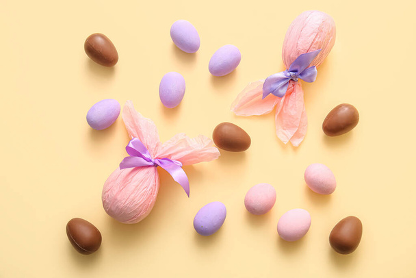 Maalattu ja suklaa Pääsiäismunat kääritty paperiin beige tausta - Valokuva, kuva