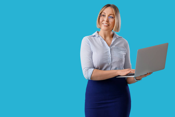Mulher de negócios madura trabalhando com laptop no fundo azul - Foto, Imagem