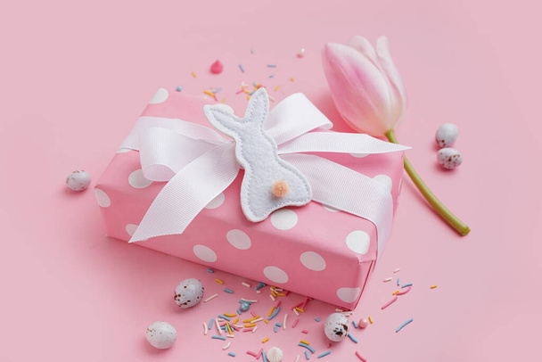 Caja de regalo con flor de tulipán y conejito de juguete de Pascua sobre fondo rosa - Foto, imagen