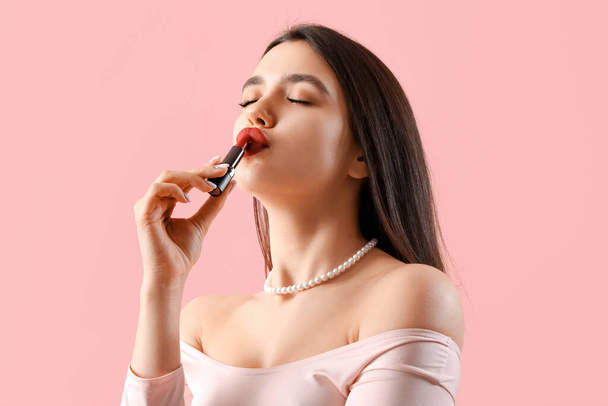 Kaunis nuori nainen suudella punaista huulipunaa vaaleanpunainen tausta - Valokuva, kuva