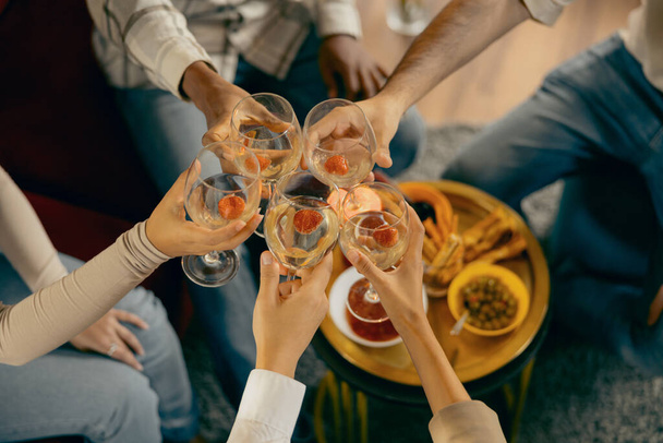 Vista dall'alto di amici che si stringono con bicchieri di vino mentre festeggiano insieme alla festa di festa - Foto, immagini