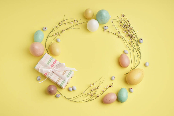 Belle couronne d'œufs de Pâques, fleurs et coffret cadeau sur fond jaune - Photo, image