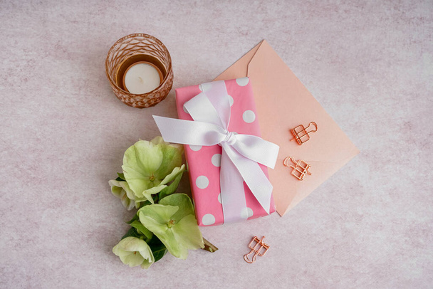 Dárková krabička s krásnými květy, obálka a svíčka na bílém pozadí - Fotografie, Obrázek